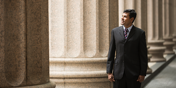 A man in a suit surrounded by stone pillars