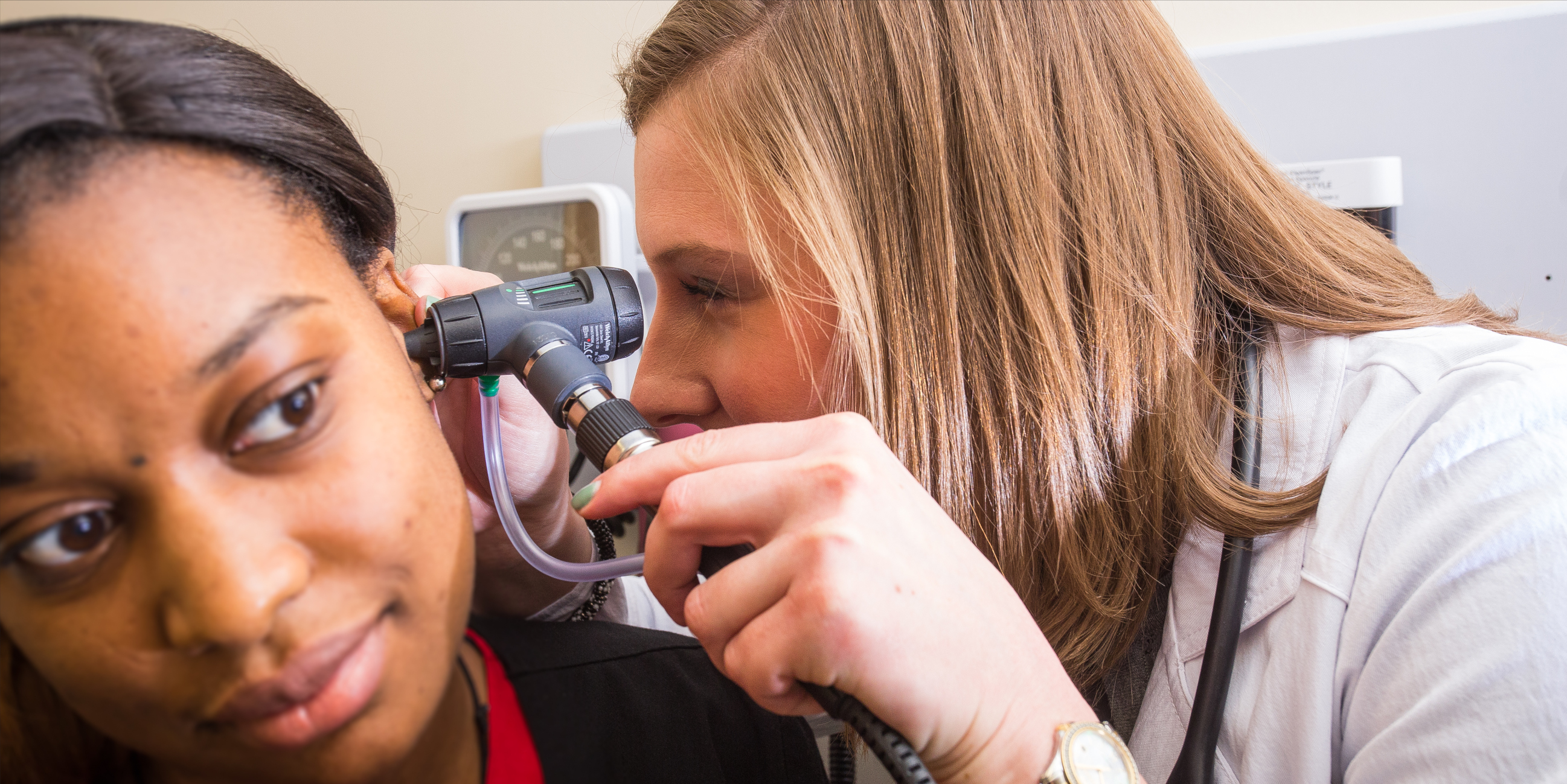 a medical professional inspects the ear of a patient