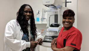 Two female medical professionals posing in front of a piece of medical equipment