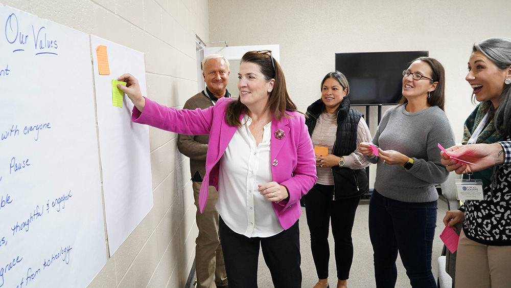 For All Seasons Associates gathered around a whiteboard