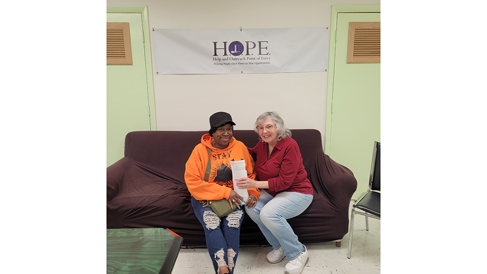 Two people on a couch under the HOPE logo sign