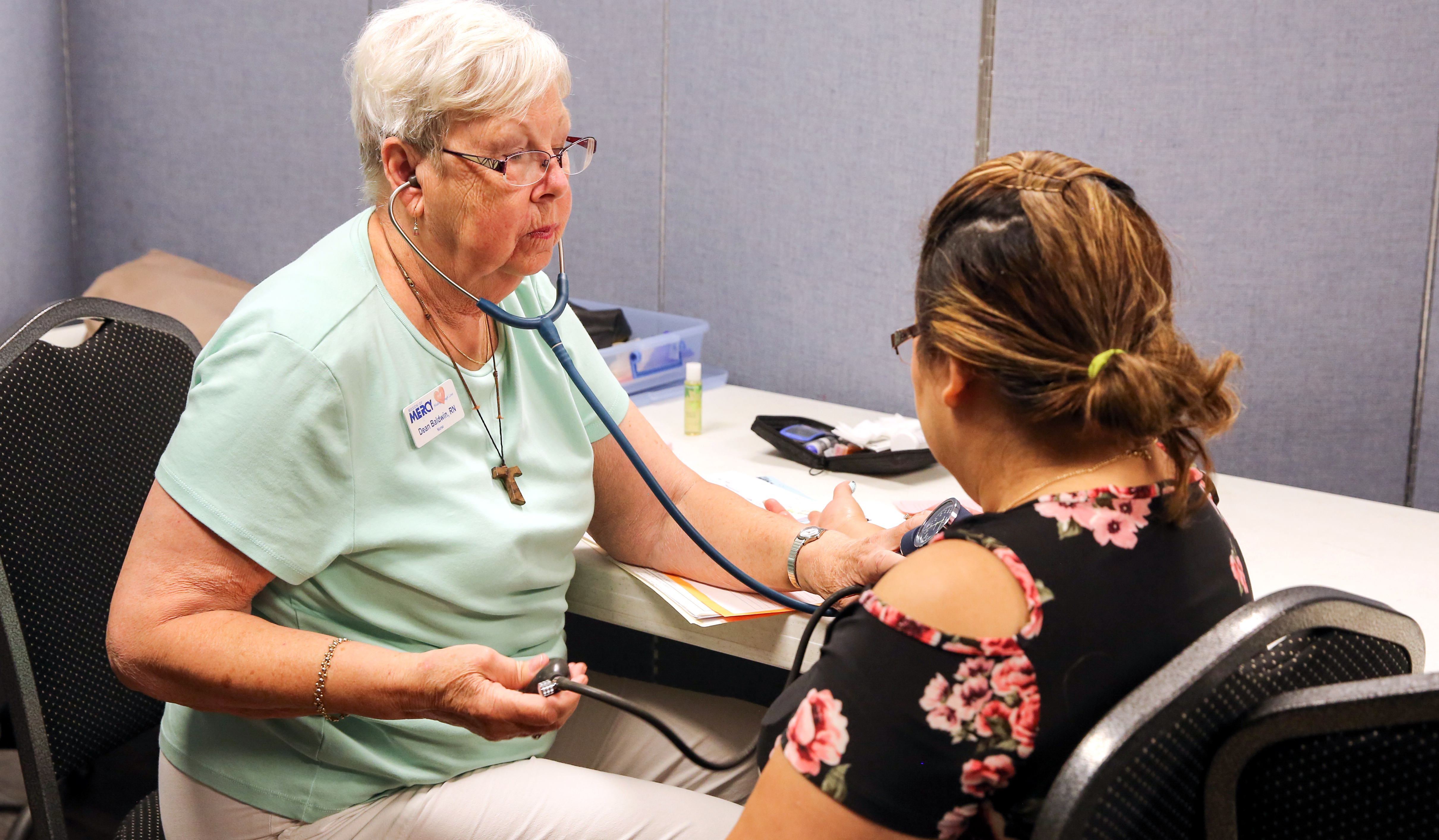 An older woman takes the blood pressure of a client