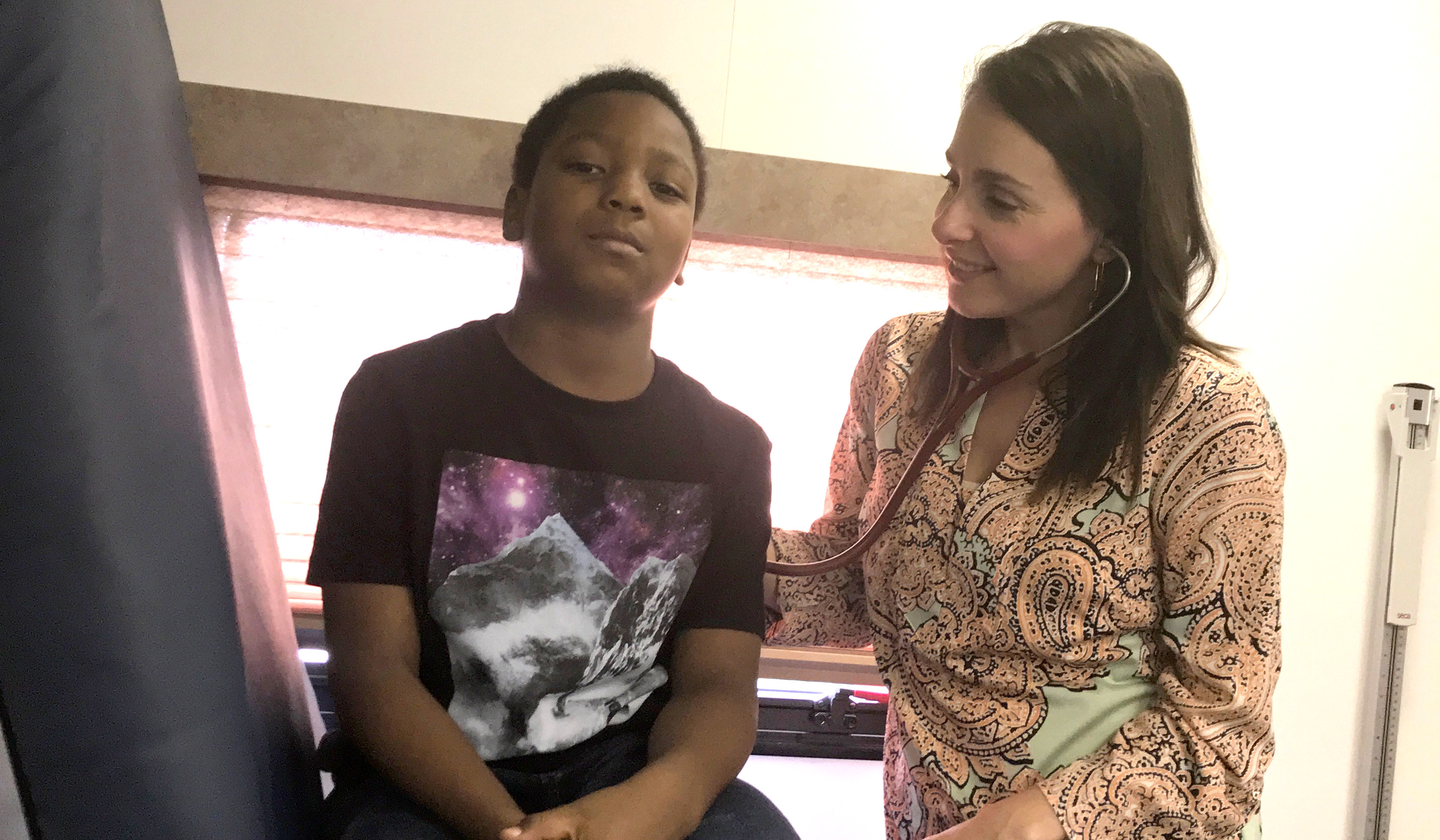 A healthcare worker listens to a child's breathing with a stethoscope