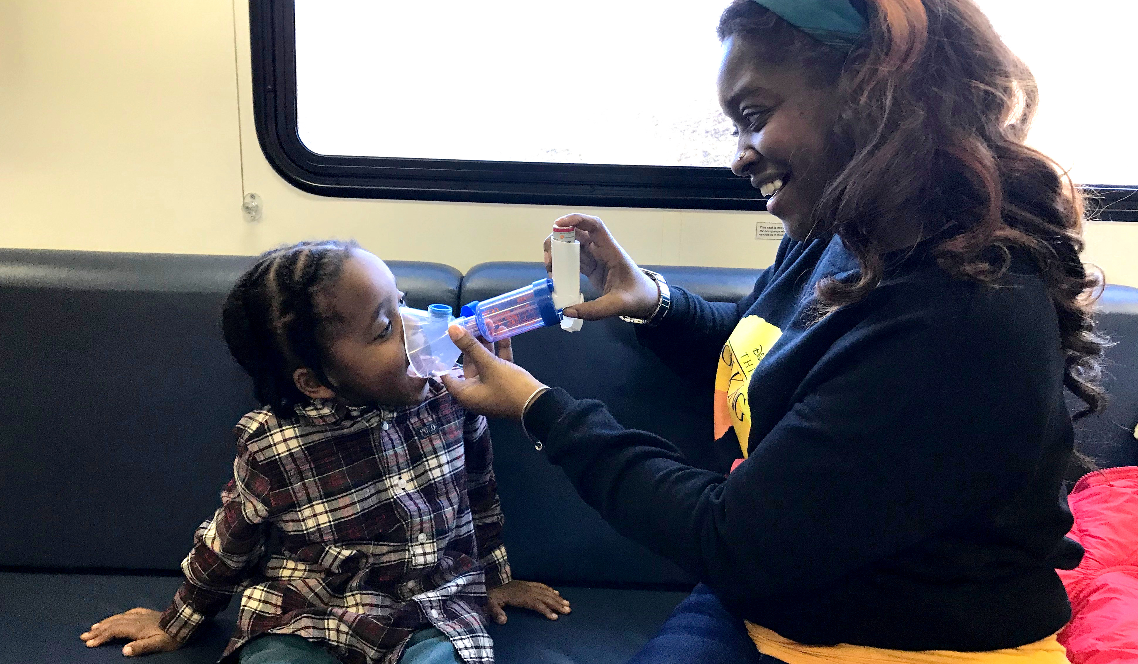 A mother holds a breathing device to her child's mouth inside the Breathmobile