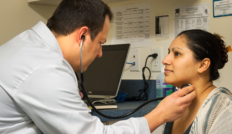 Medial professional using a stethoscope on the neck of a patient