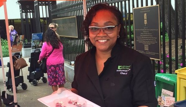 A smiling woman holding a tray of snacks