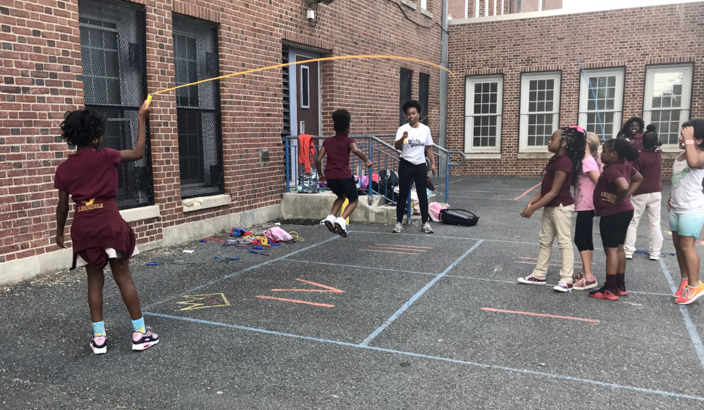 Girls play jump rope on a playground lot