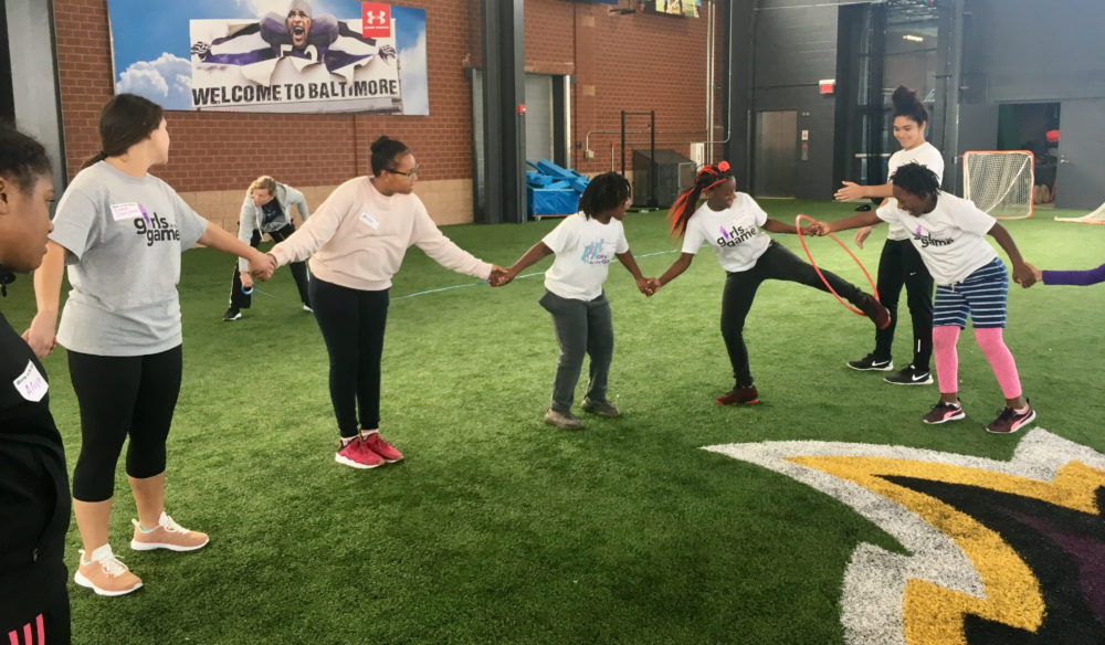 girls hold hands during a game in an indoor athletic facility