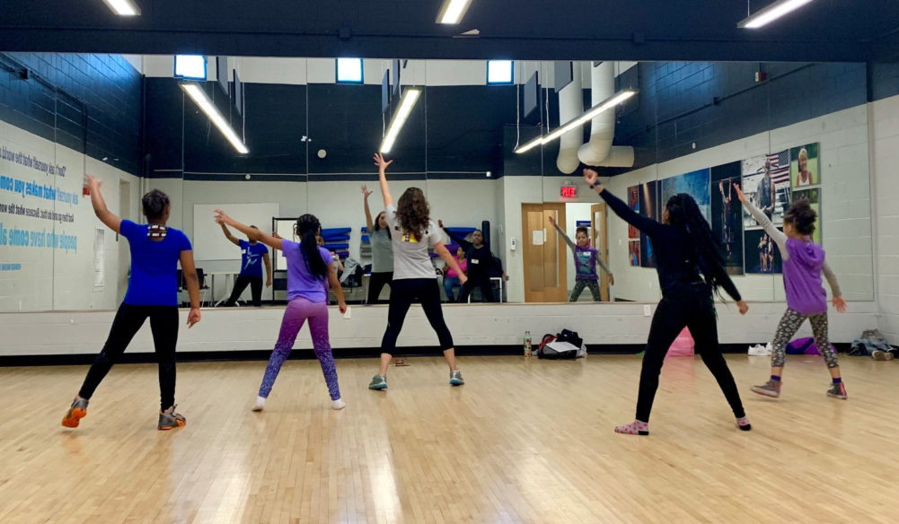 girls practice aerobics in a gym setting