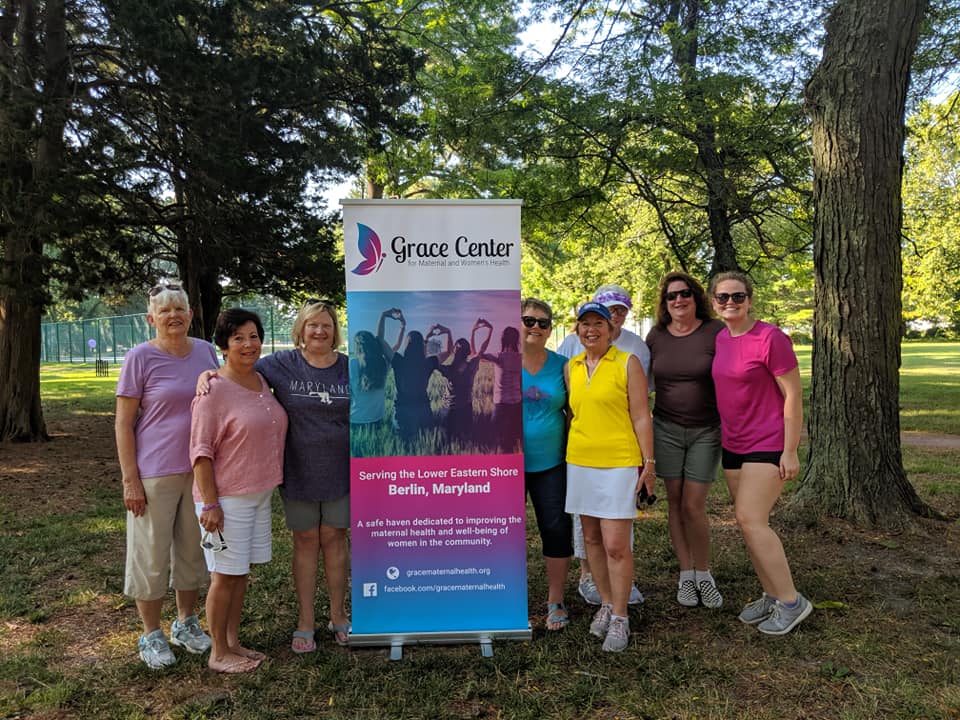 group of women with a pull up banner for Grace Center