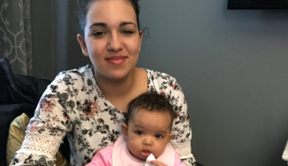 A woman holding an infant both looking at the camera