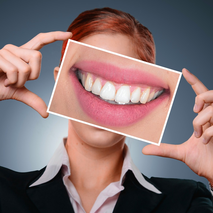 Woman holding a photograph of her smile over her face