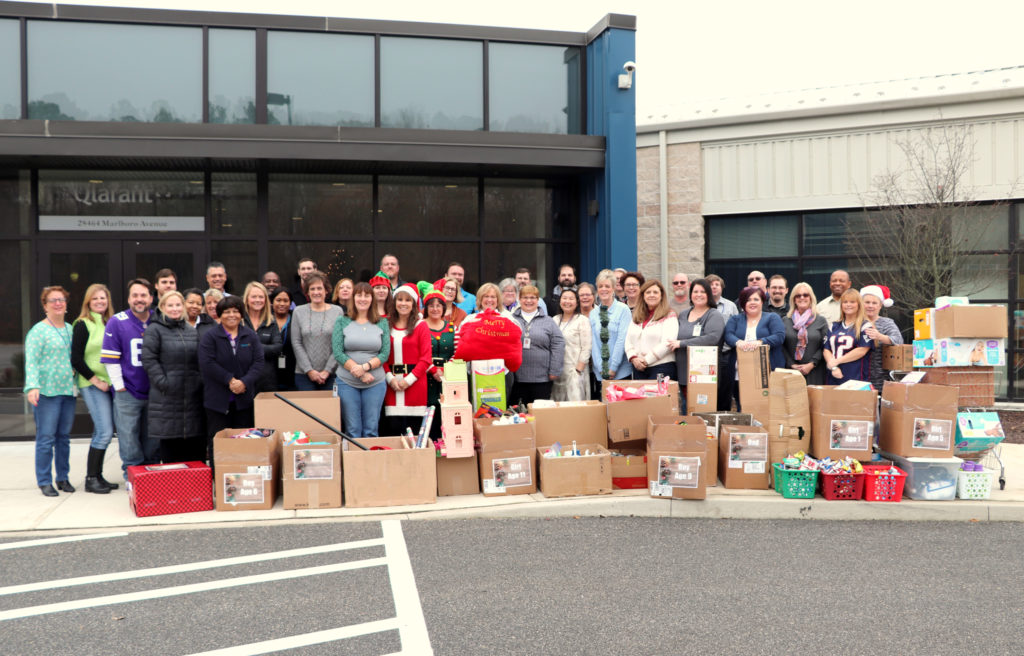 Qlarant Associates grouped around gifts in front of office building