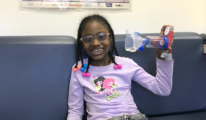 Child on Breathmobile holding an asthma inhaler