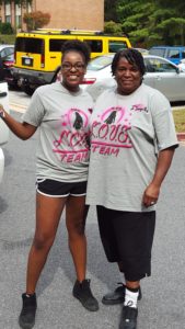 Two women standing in a parking lot wearing matching team shirts