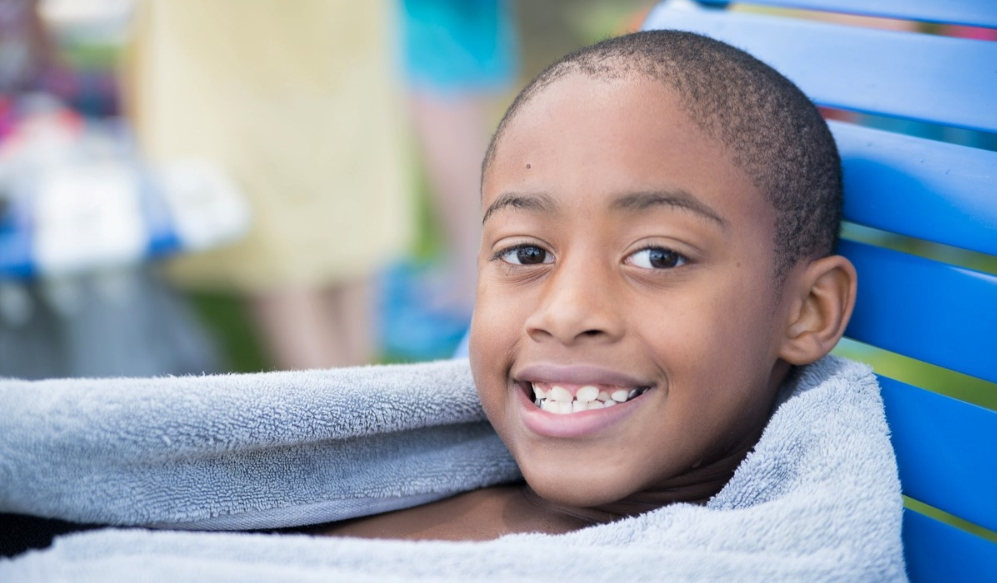 a young african-american boy wrapped in a towel smiling