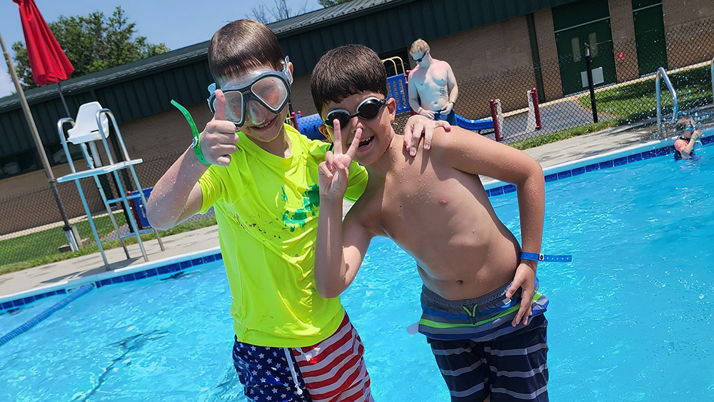 Two boys mug for the camera by the pool