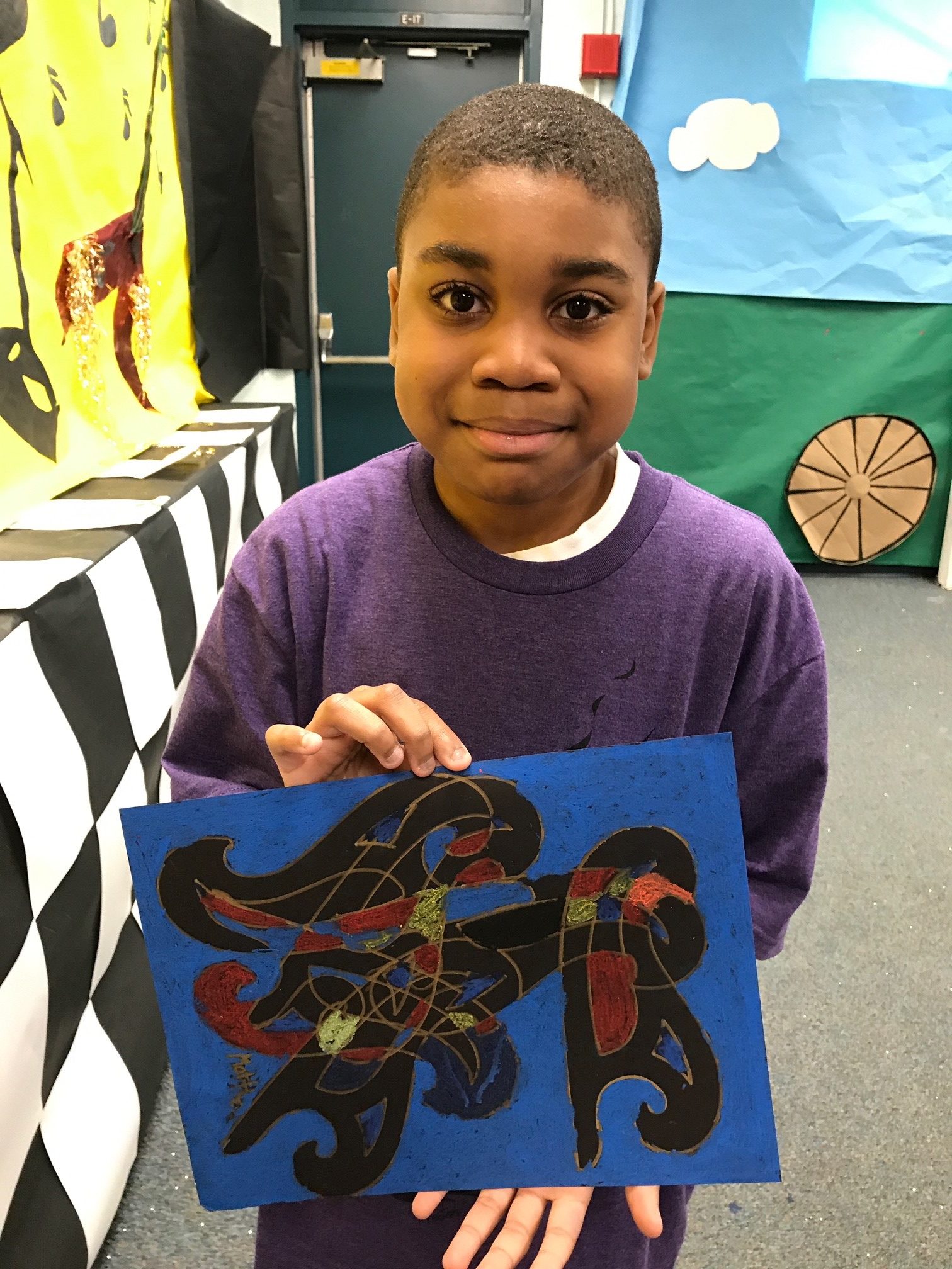 a young black boy holds his art