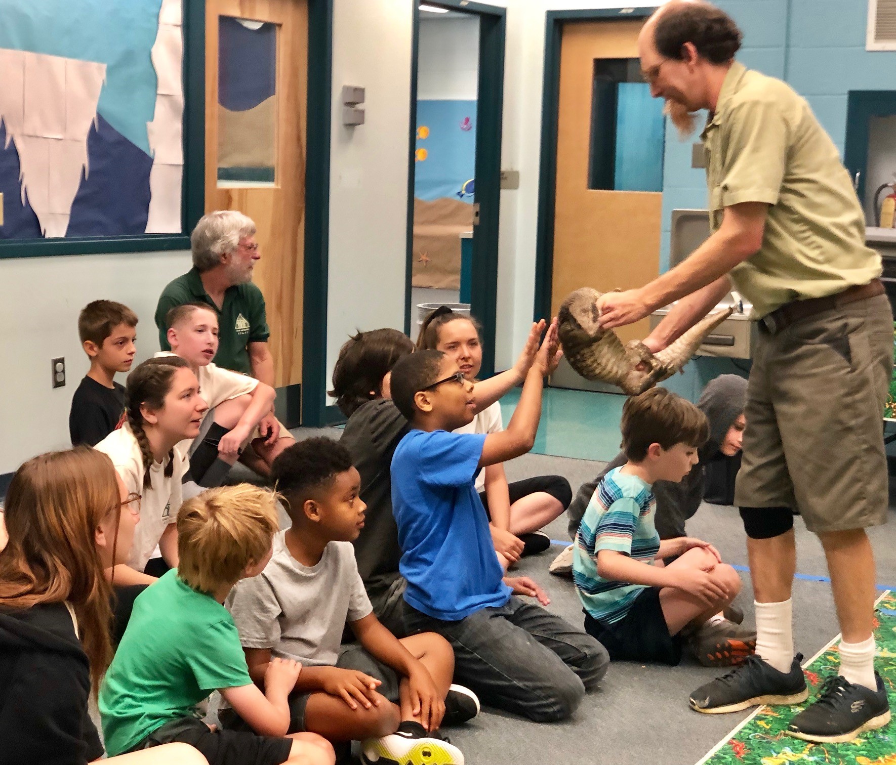 a group of kids touches a reptile held by a presenter