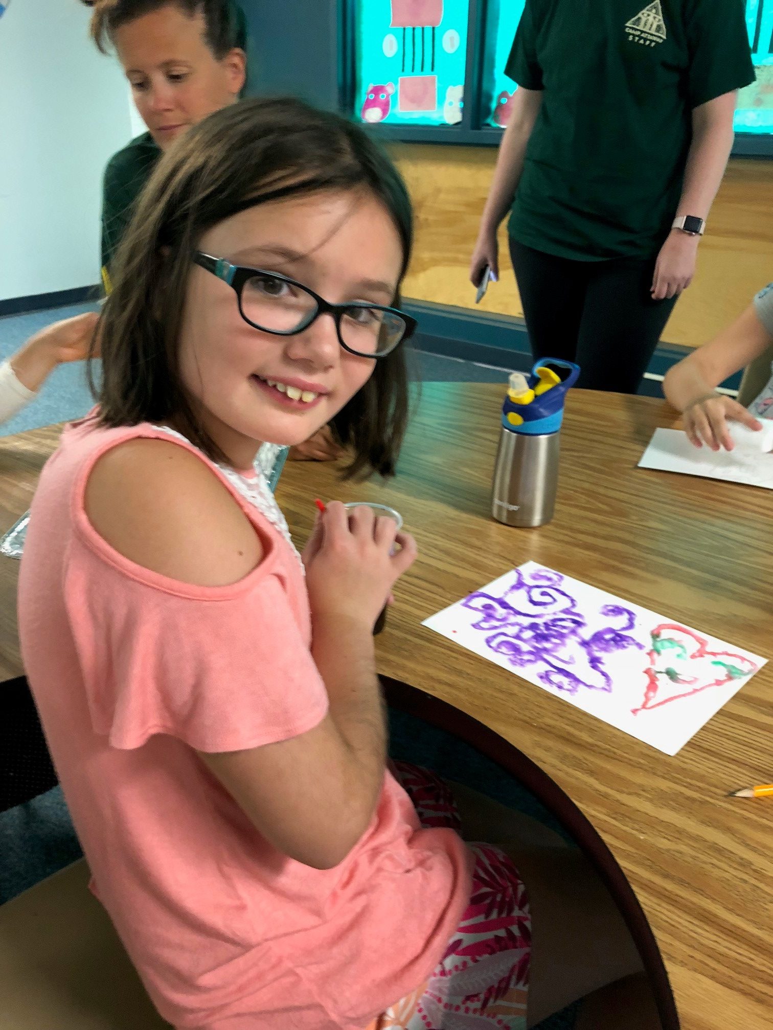 a girl in glasses shows off her art