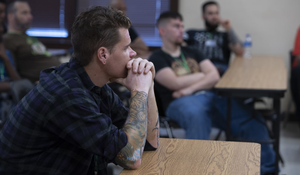 a man in a class leaning on the desktop listening