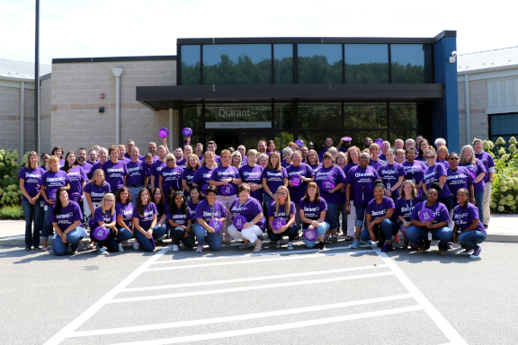 Large group of Qlarant associates all wearing purple shirts