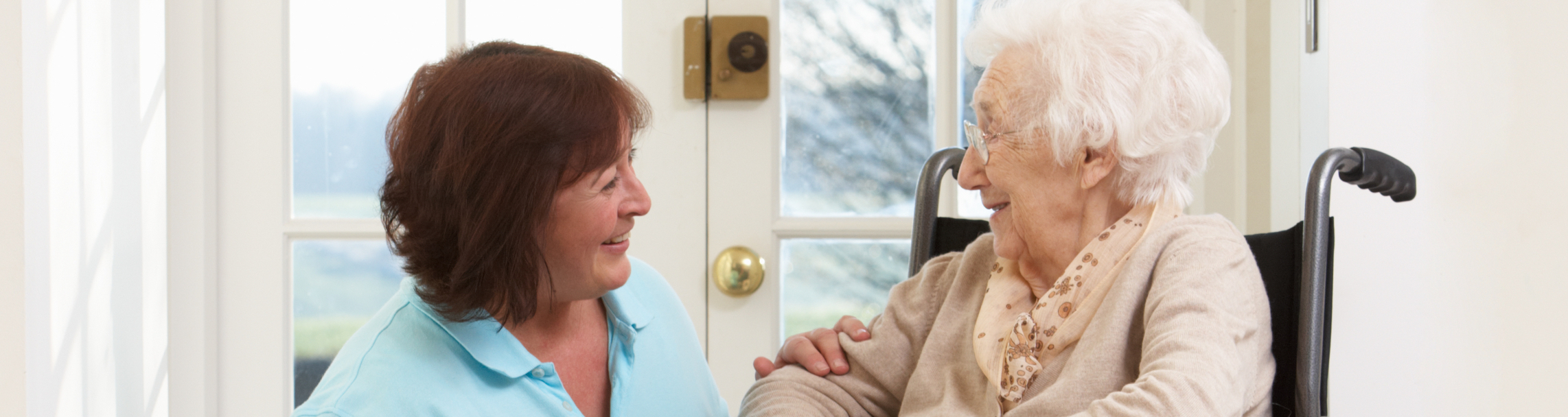 Elderly woman in a wheelchair speaking with a caregiver