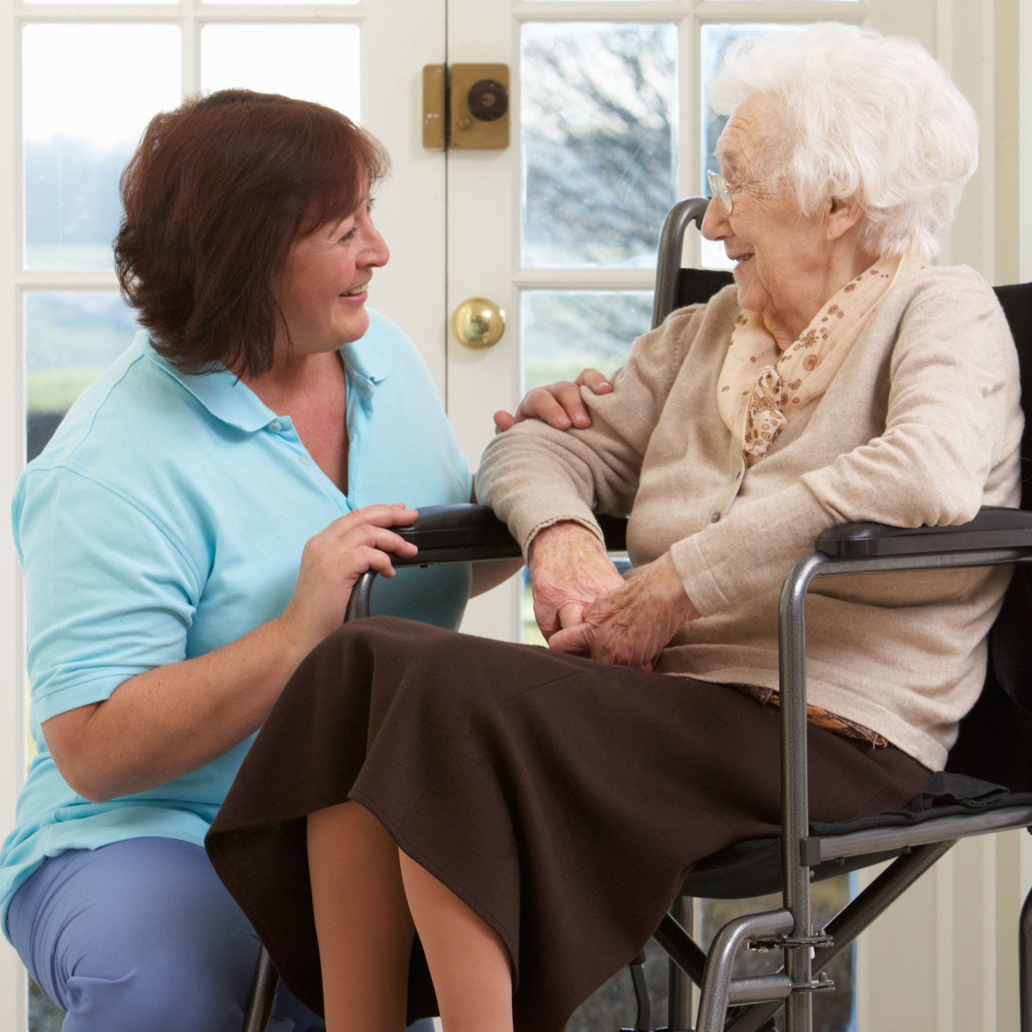 Elderly woman in wheelchair speaking with caregiver