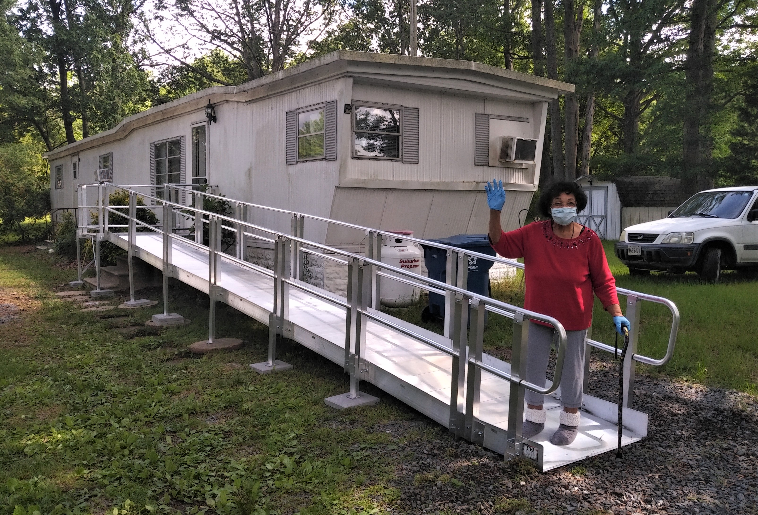 A mobile home with an new ramp installed and the homeowner on it waving