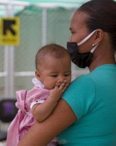 masked mother holds infant