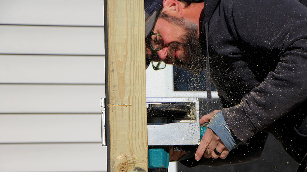 A man cuts a post with a power saw