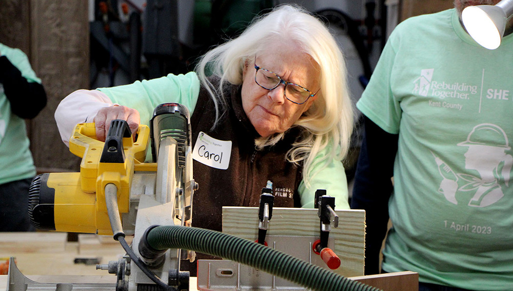 A volunteer works a table saw