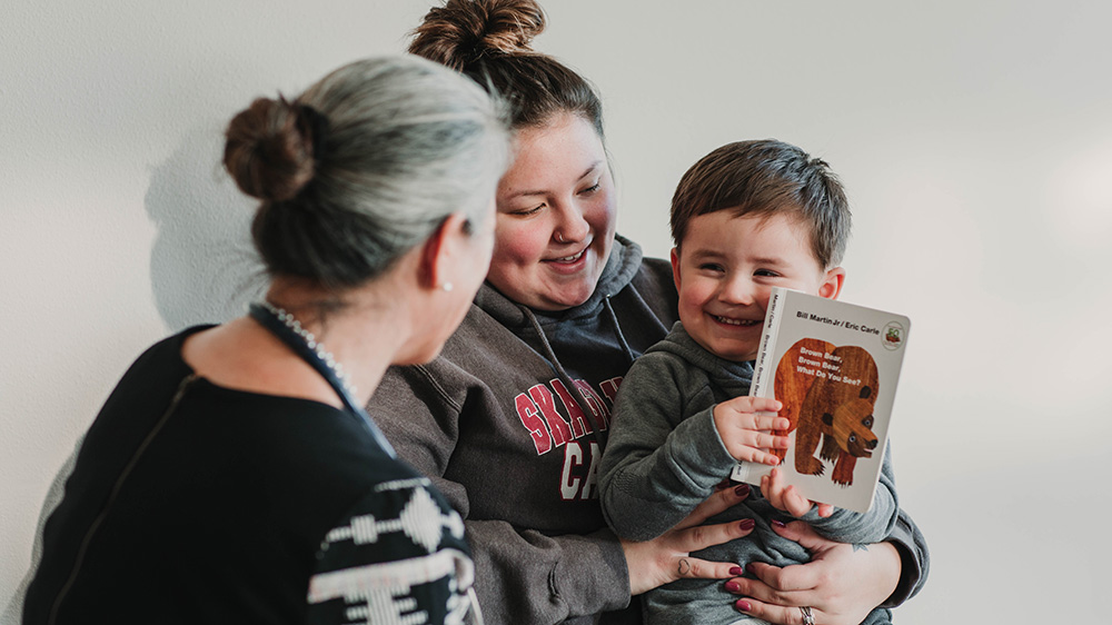 Two women and a child with a book