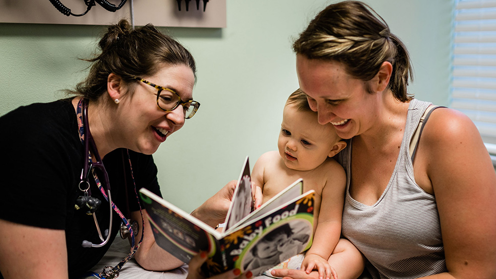 Two women reading with a baby