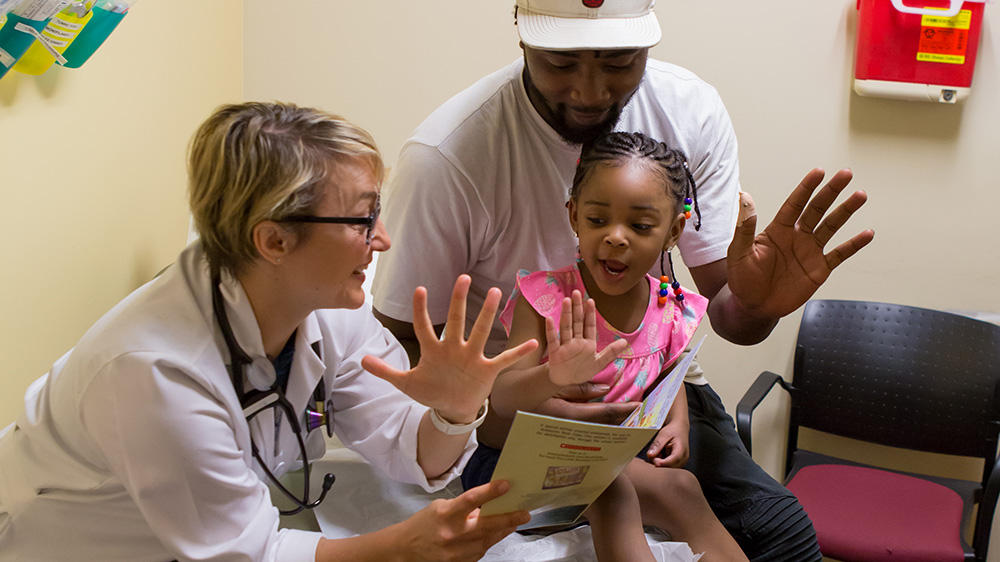 A doctor helping a child count from a book