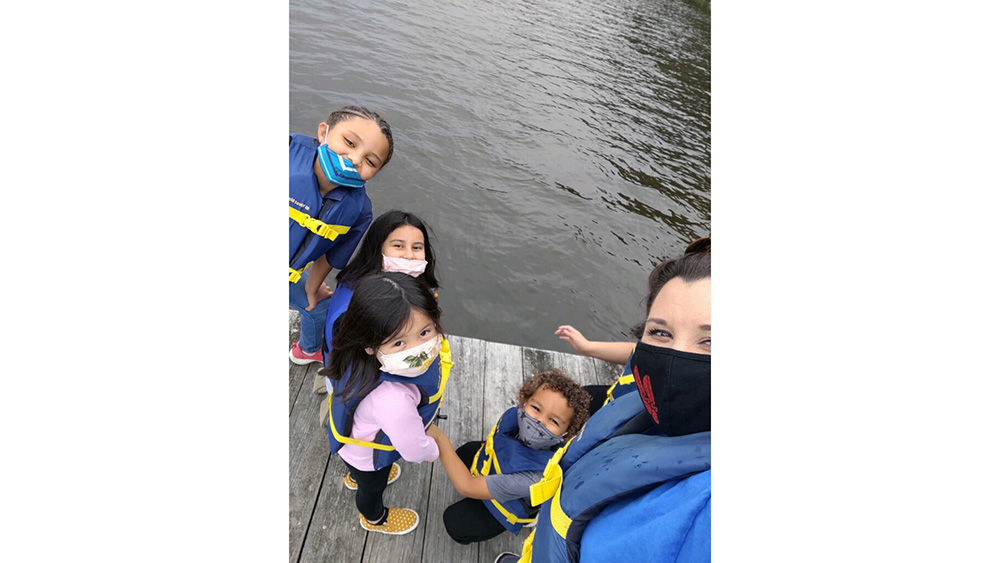 A woman with four children in lifejackets on a dock