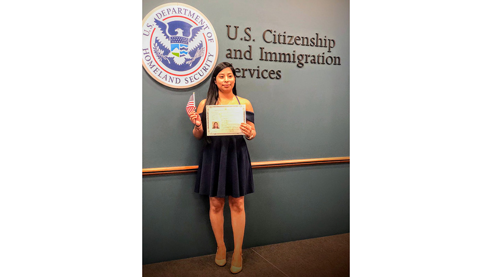 A woman holding her citizenship certificate at the U.S. Citizenship and Immigration Services office