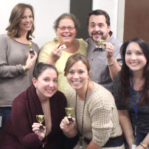 Group of Qlarant Associates holding tiny trophies