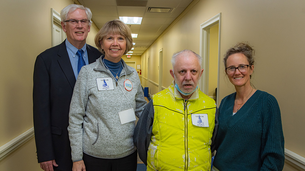 Four people posing for a photo in a hallway