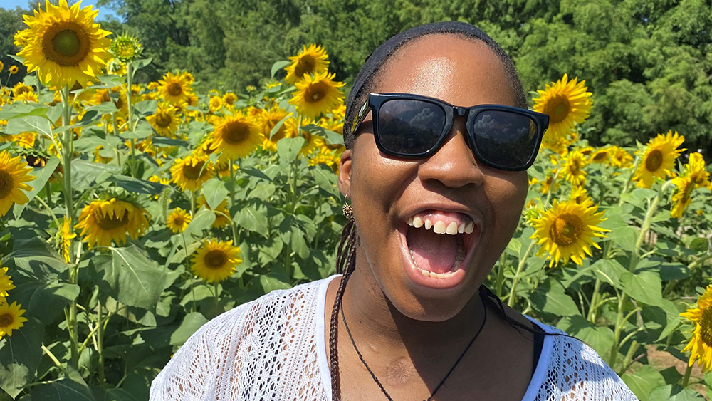 A woman smiling broadly in a sunflower field