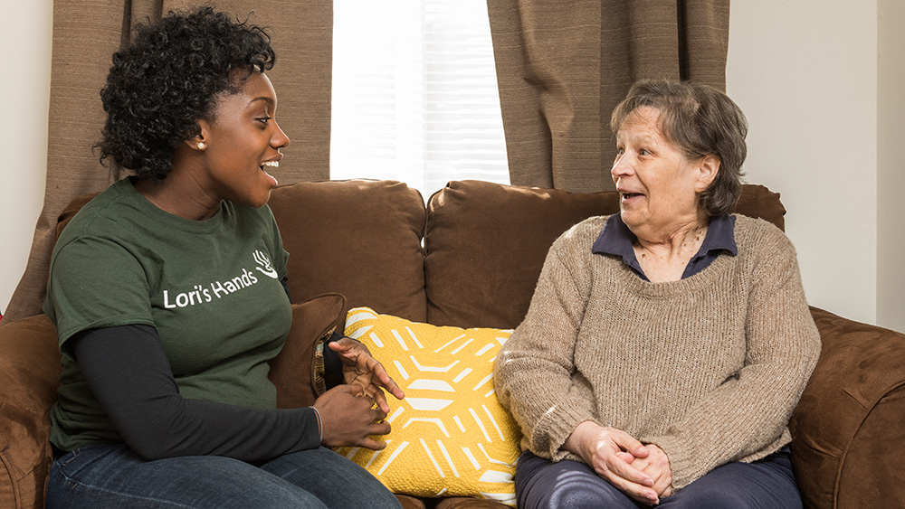 A client and a volunteer talk on a couch