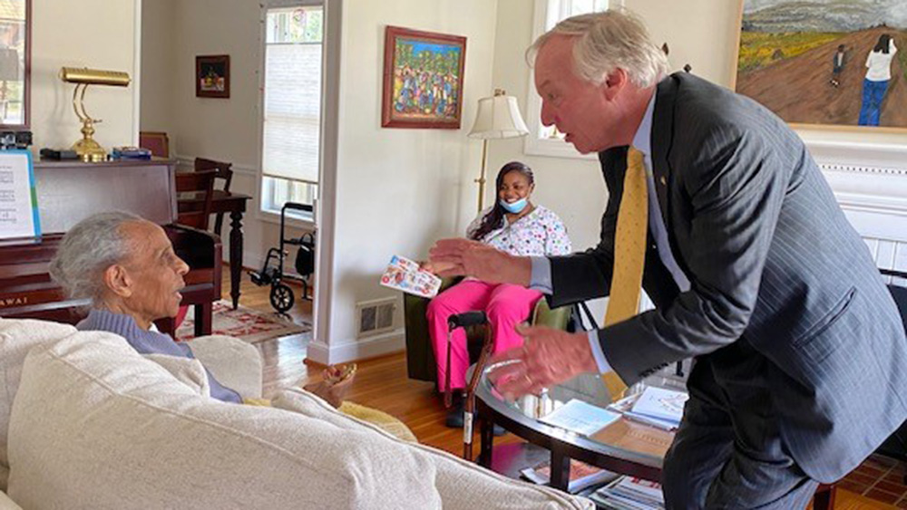Peter Franchot in a client's home handing her something