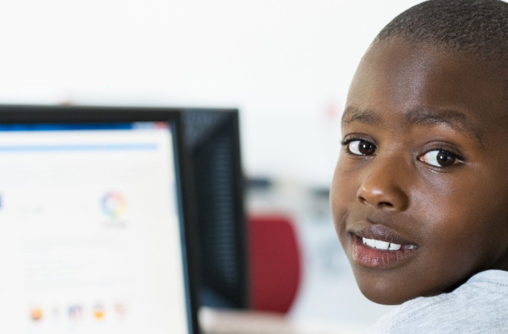 Boy looking over his shoulder at a computer