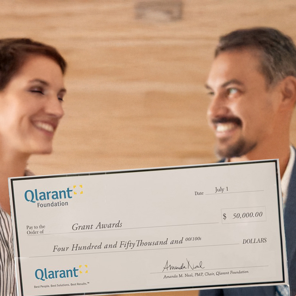 Two people holding a large grant check